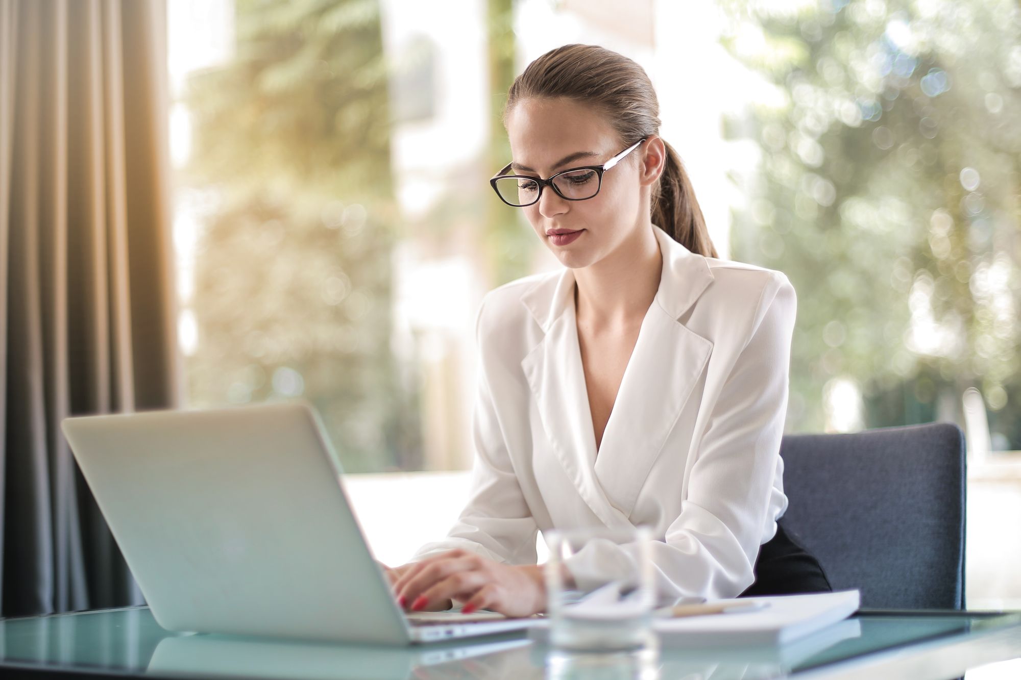 Compliance manager working on a laptop at a bright office desk